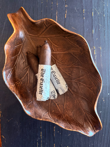 Cigar with 'The Gazette' wrapper on a leaf-shaped wooden tray